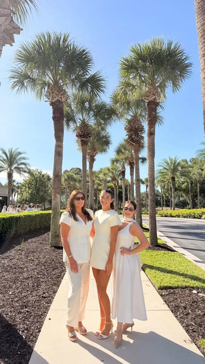 Renaé and two friends dressed in white under palm trees