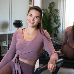 Renaé sitting on a Pilates reformer in the studio