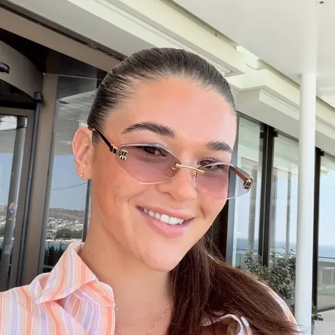 Renaé smiling in a striped shirt and sunglasses at a hotel